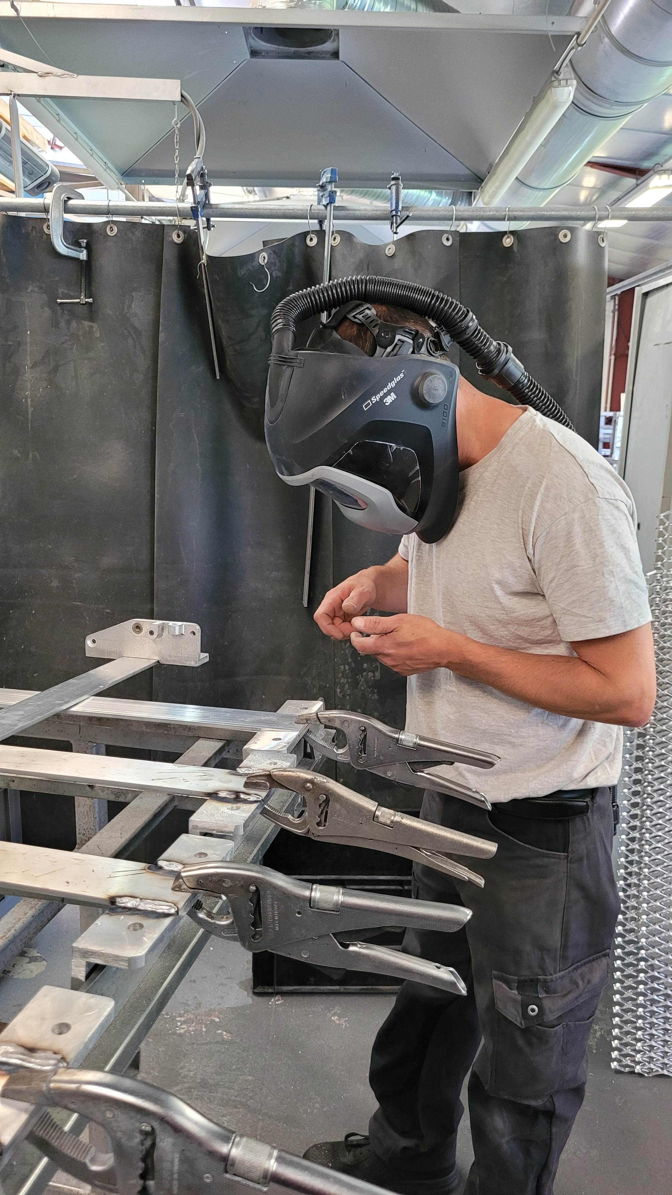 Salarié reproduisant le geste douloureux avec son casque de soudure, après la consultation